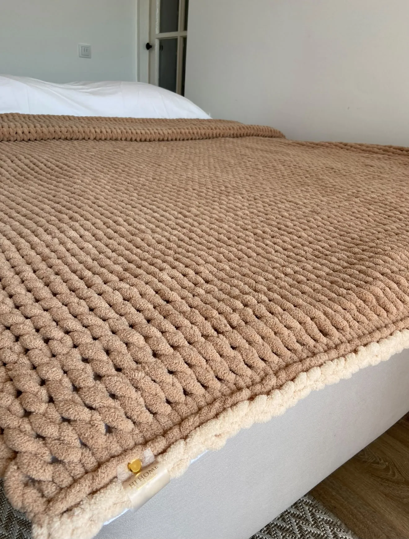 Warm brown knitted blanket laid across a bed
