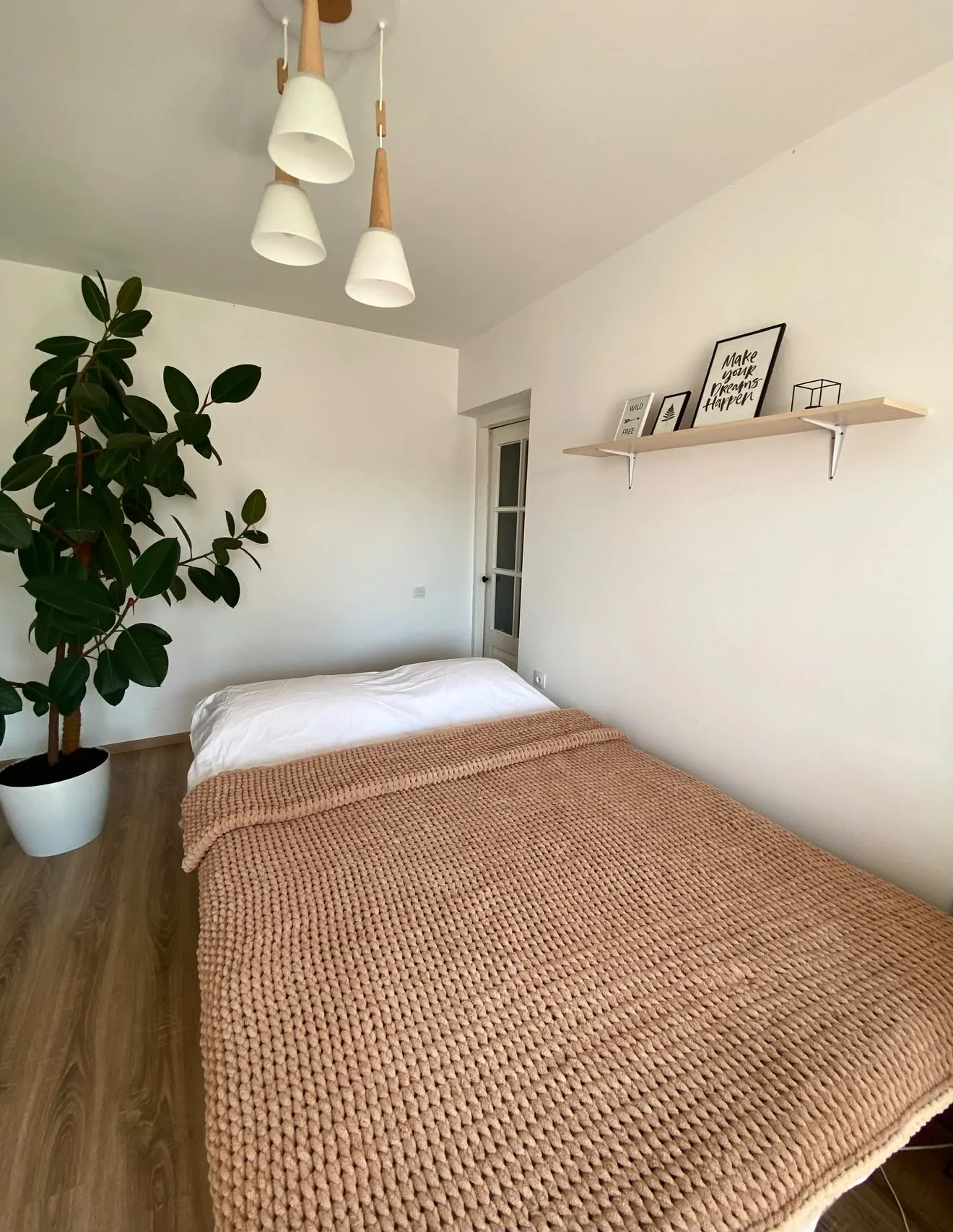 Camel coloured blanket laid over a bed in a bright room
