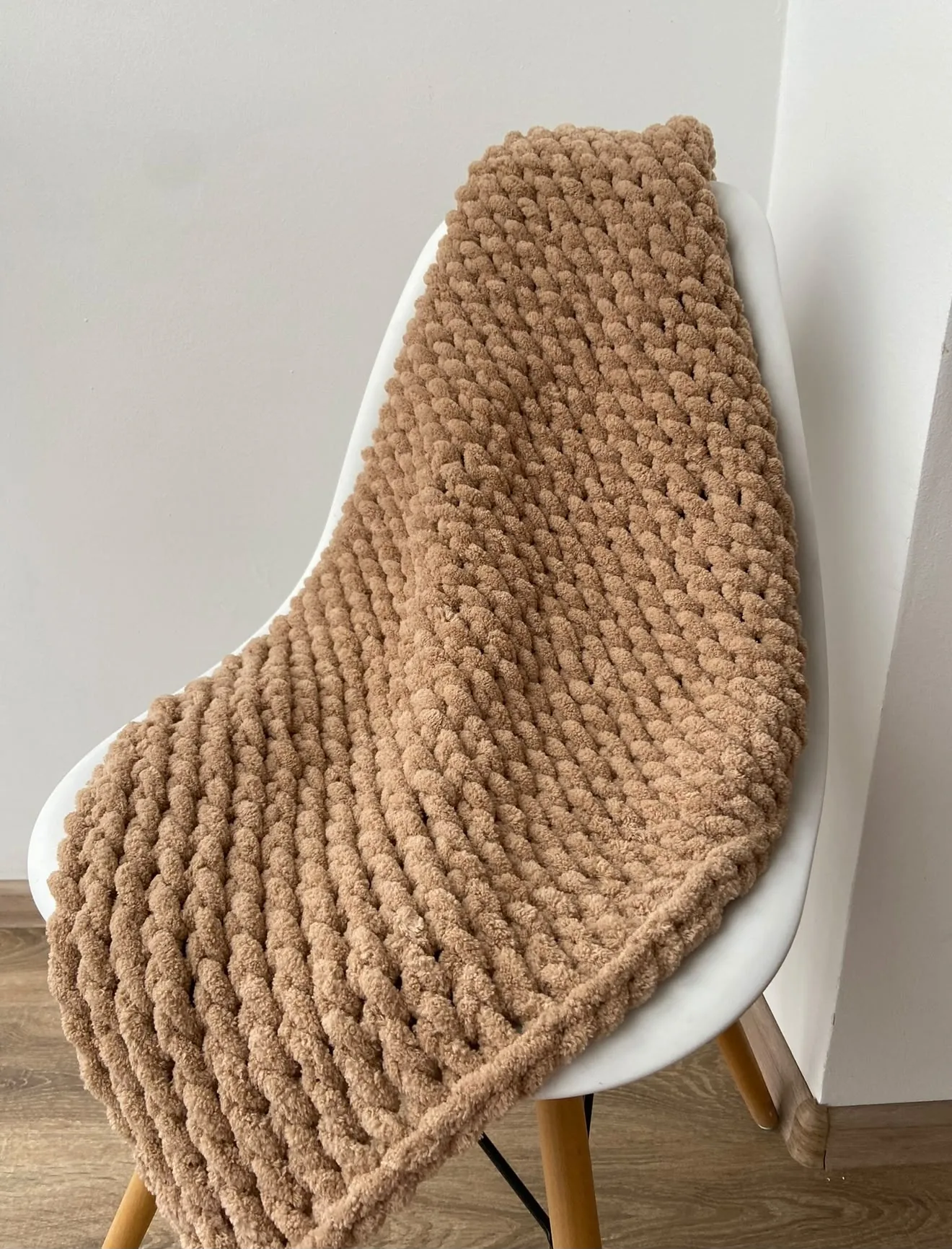 Camel coloured knitted blanket draped on a chair