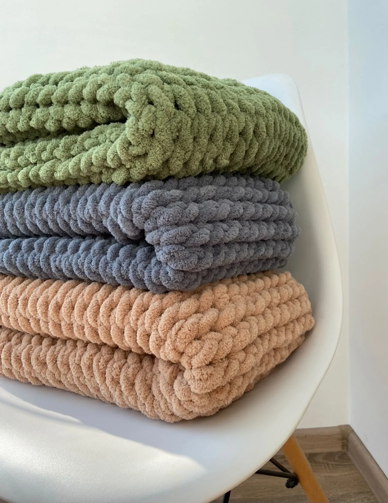 Blankets stacked in green, cream, blue and peach