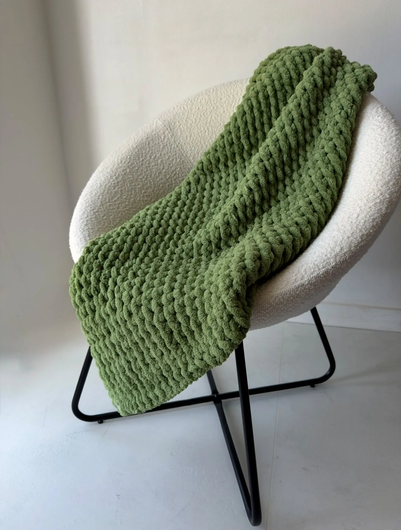 Leaf green knitted blanket draped over a chair