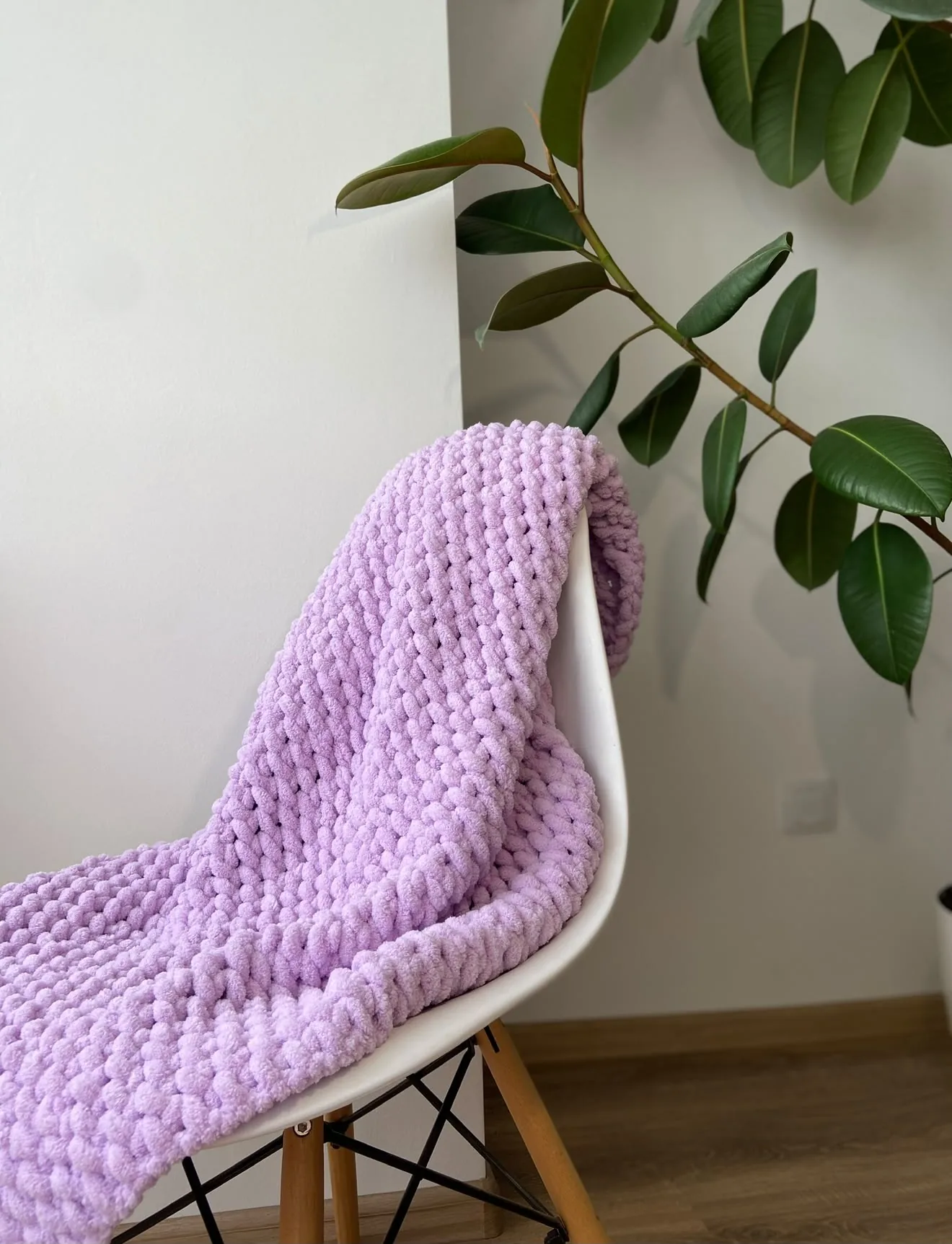 Light purple knitted blanket hanging over a chair