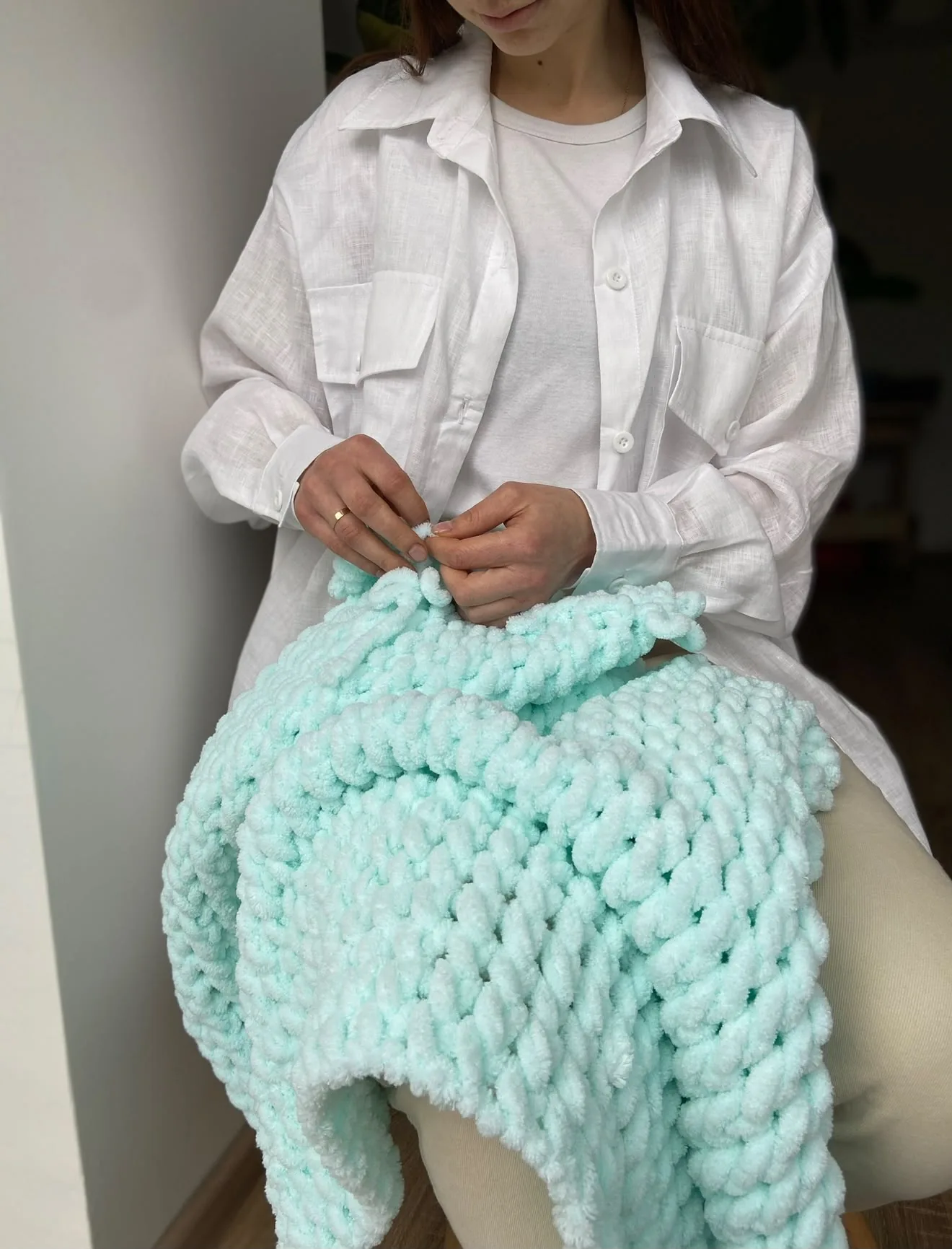 Liliia knitting a mint coloured blanket by hand