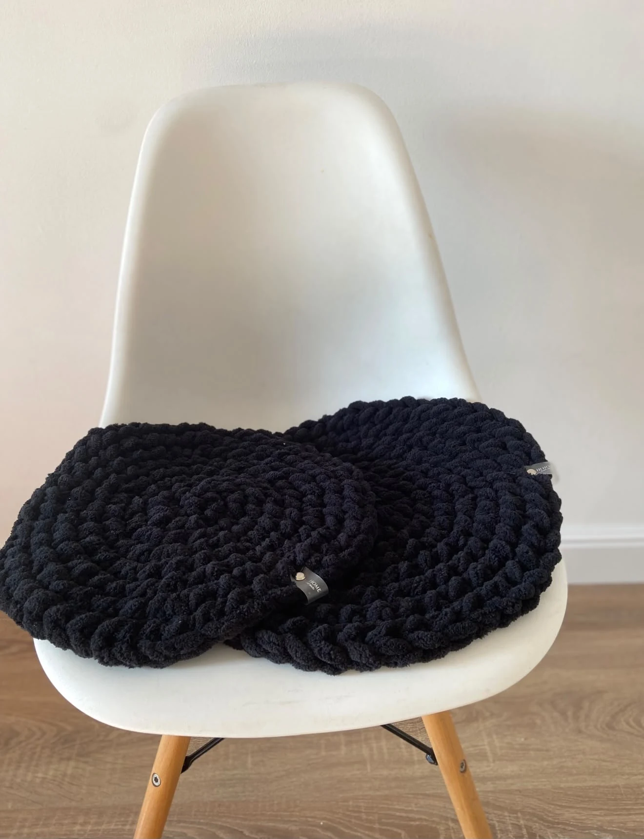 Deep black chunky knit displayed on a white chair