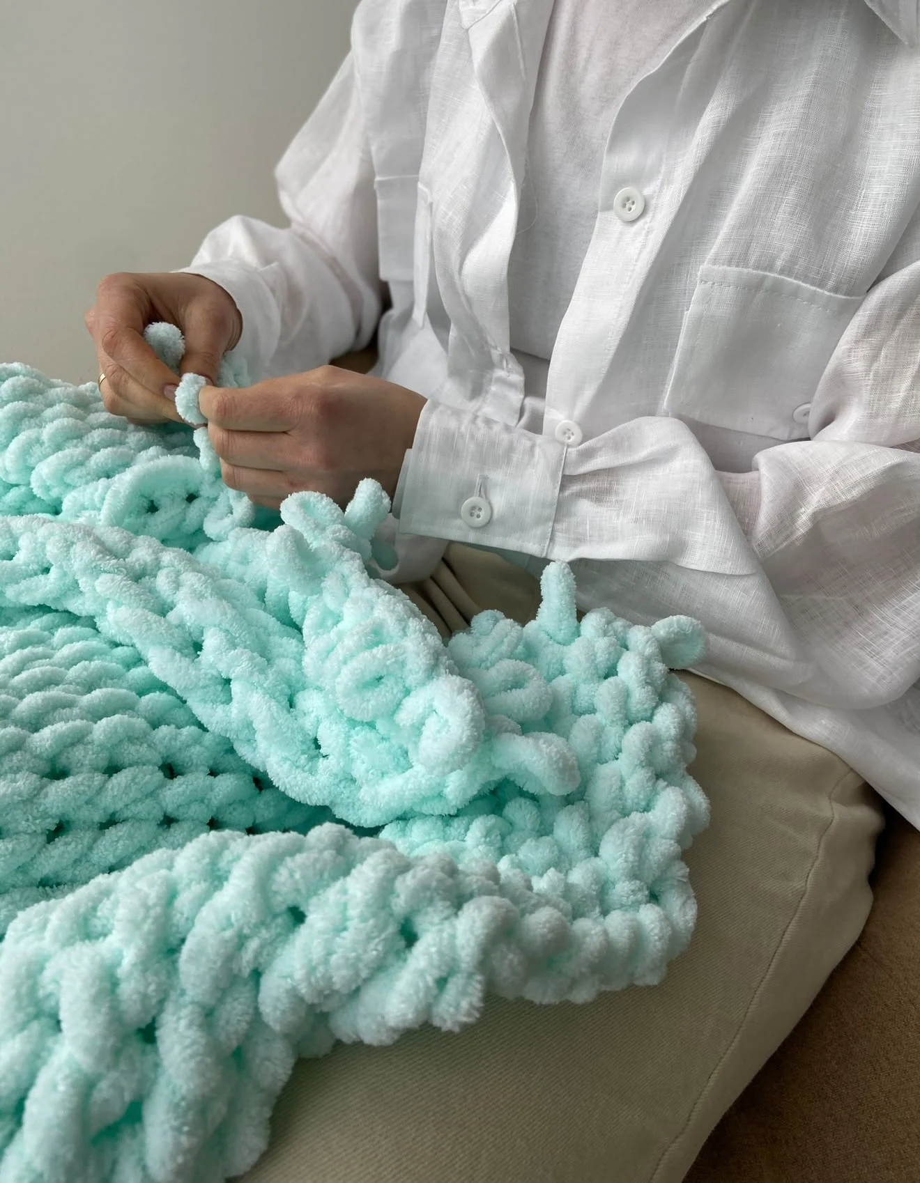 Liliia knitting a soft mint blanket by hand