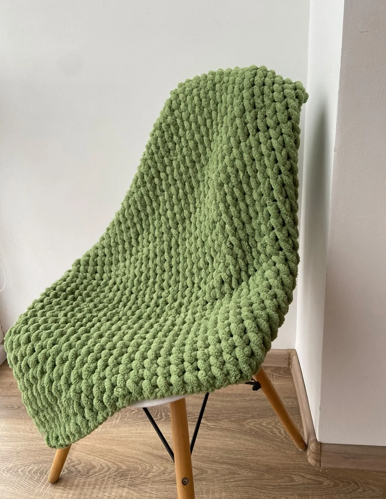Olive green knitted blanket on a white chair