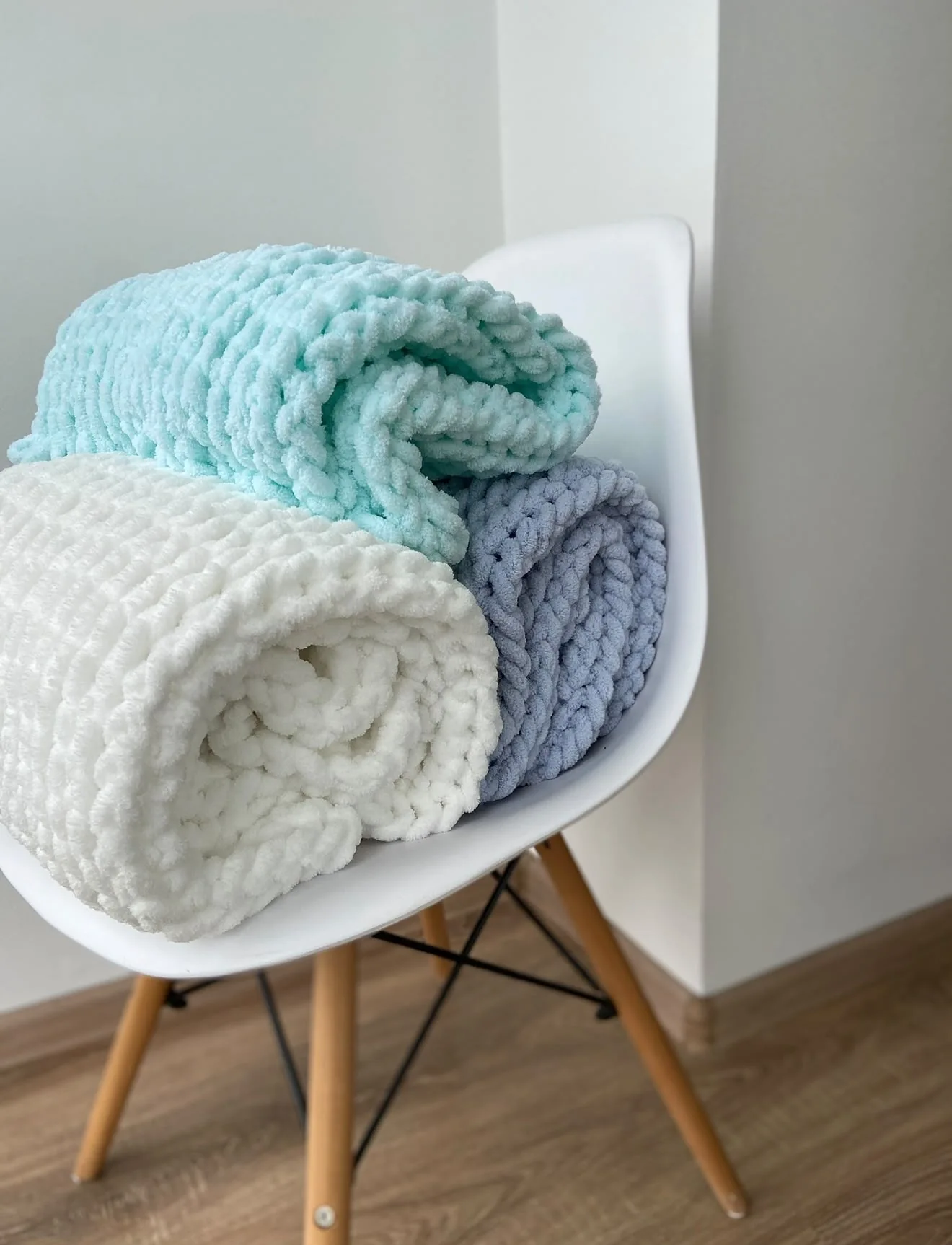 Stack of knitted blankets in green, blue, grey and peach