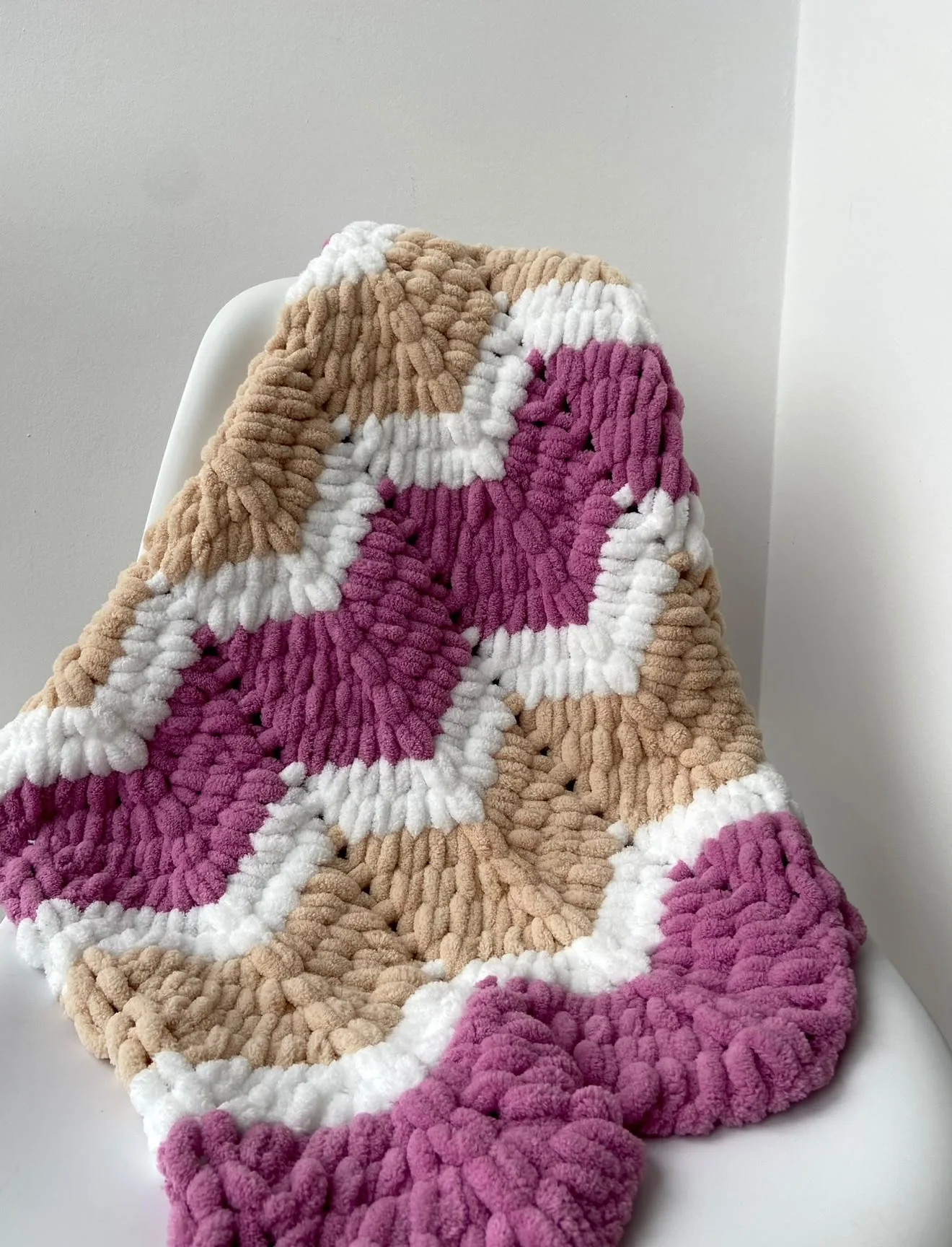 Pink, cream and sand-coloured patterned blanket draped over a chair