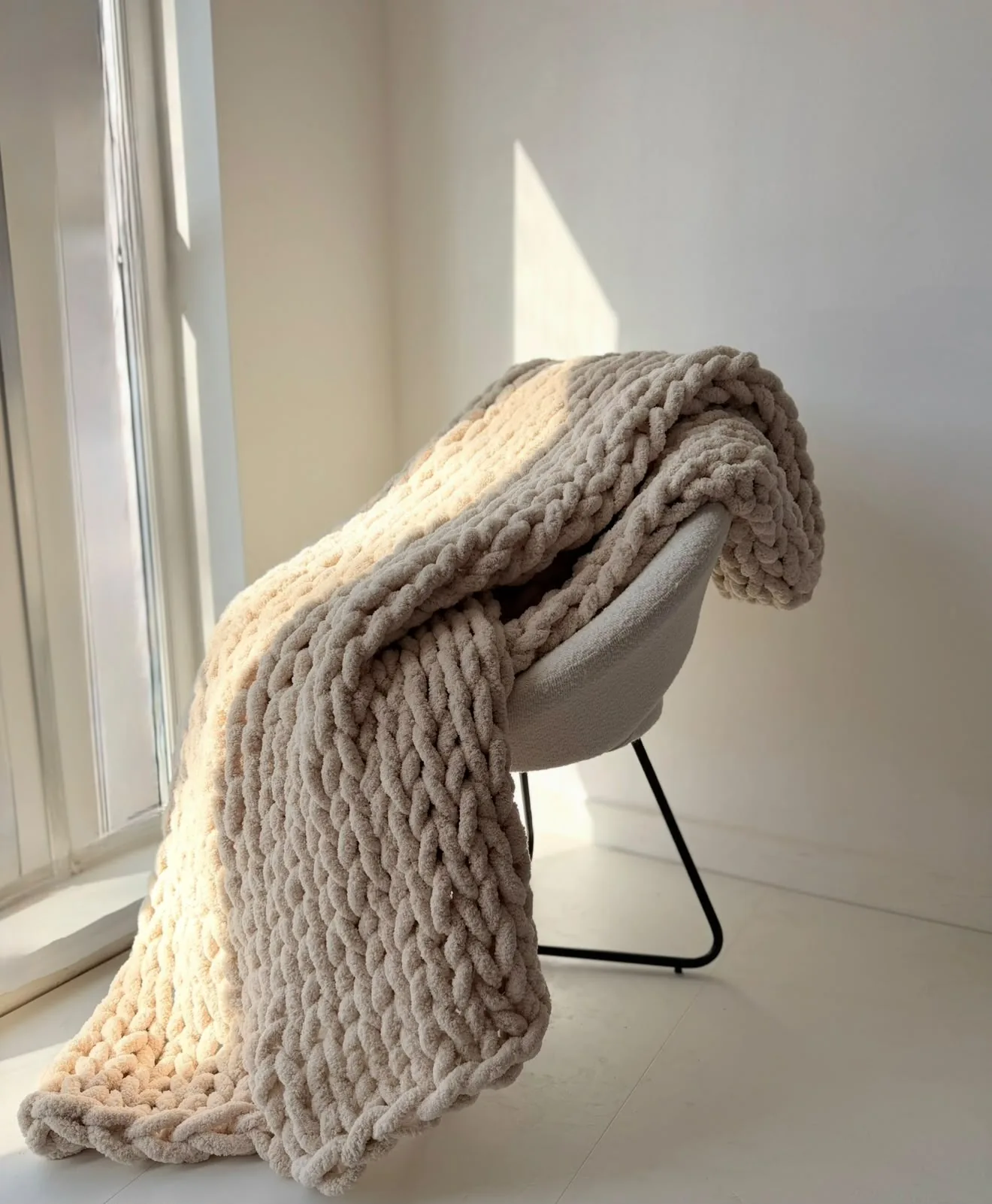 Stone coloured knitted blanket draped over a chair