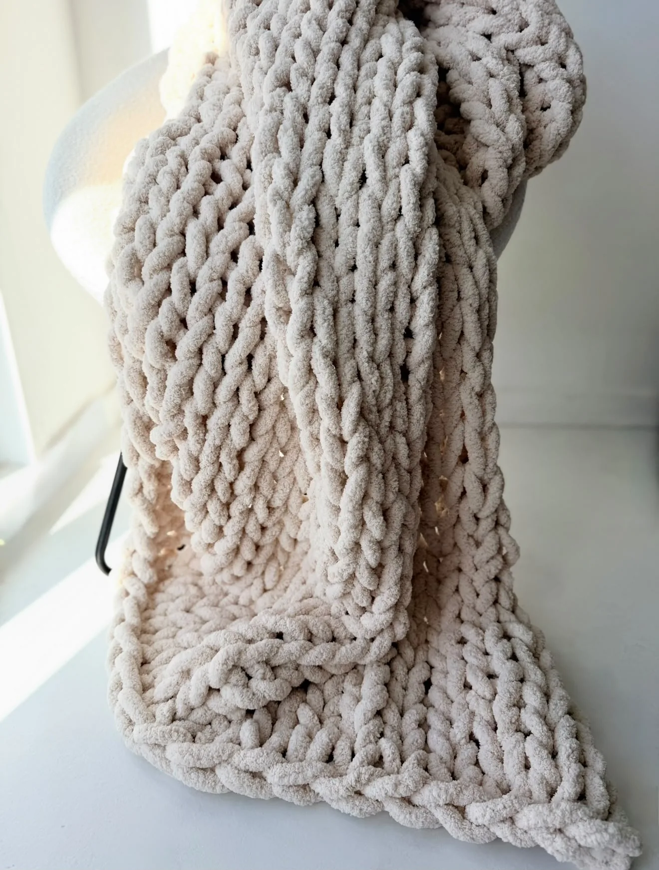 Close view of the stitches on a stone coloured blanket