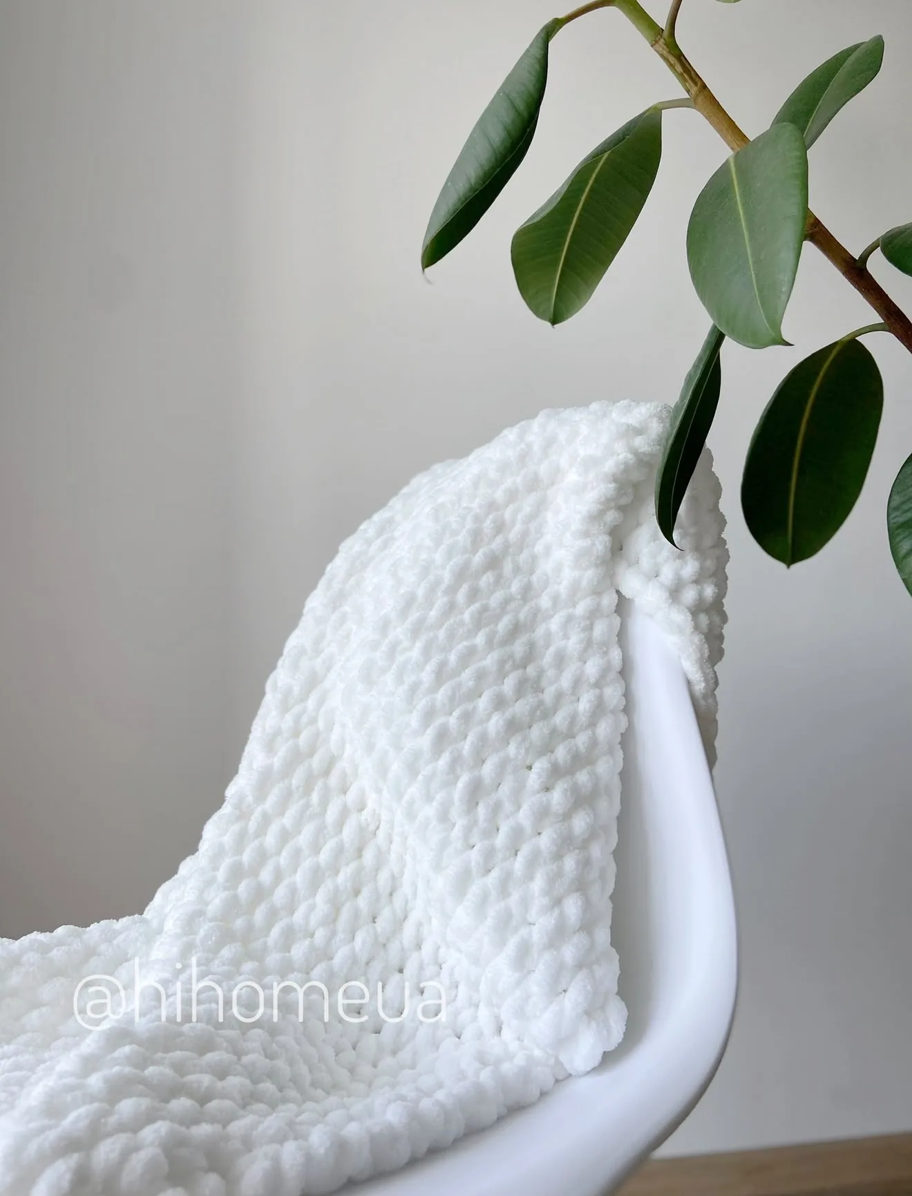 White knitted blanket folded on a chair
